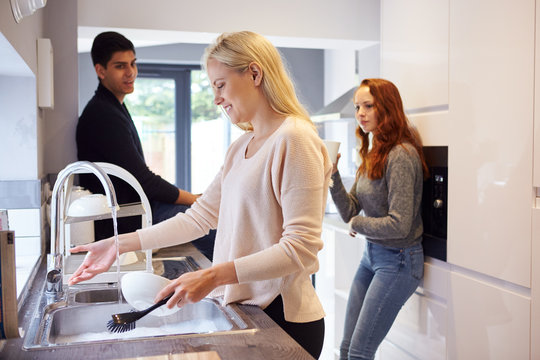 Group Of College Student Friends In Shared House Kitchen Washing Up And Hanging Out Together.jpg