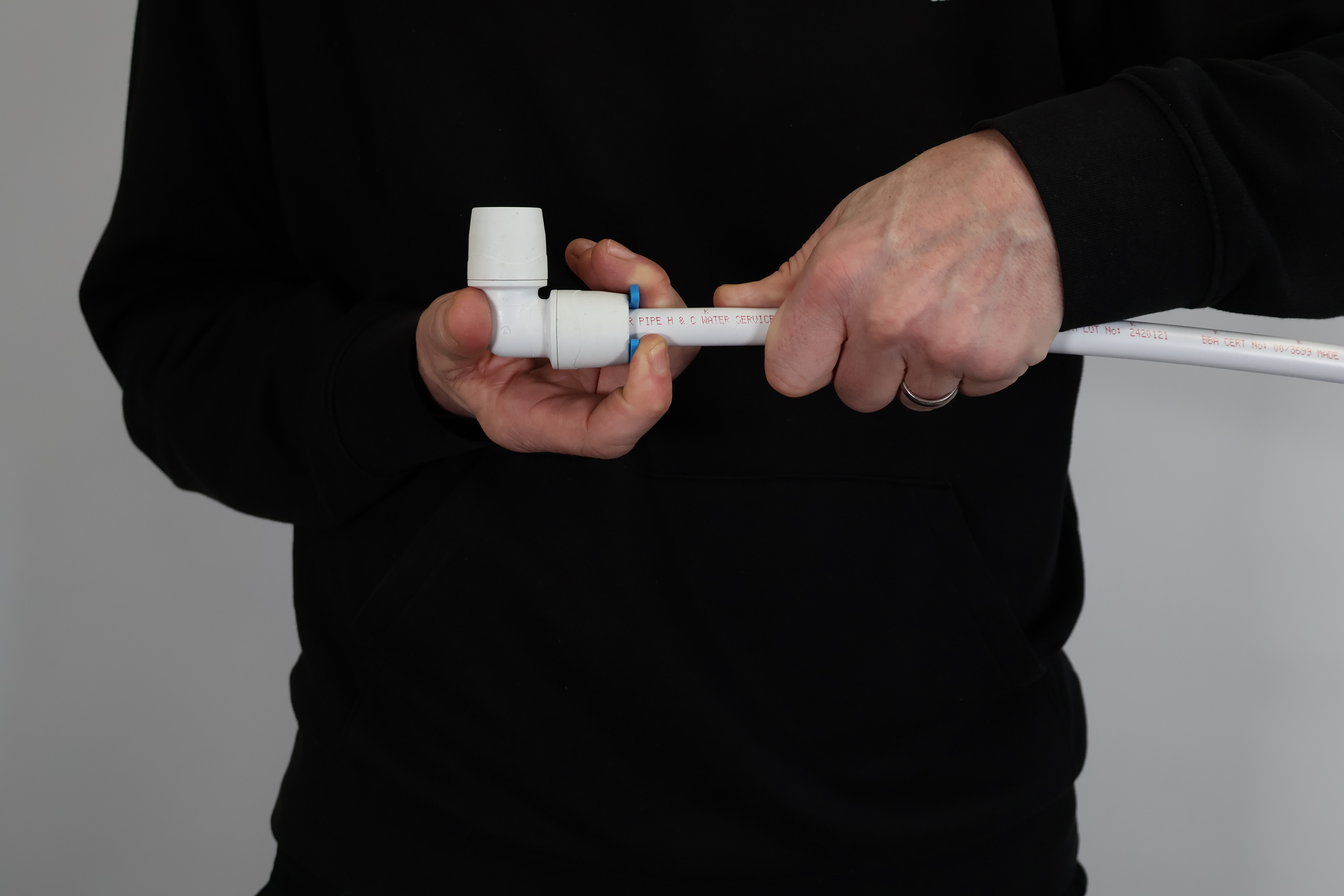 Close-up of a PolyMax push-fit elbow being checked for a secure fit. Proper hand-tightening ensures the pipe has passed through the grab ring and O-ring, preventing leaks and ensuring long-term joint integrity.