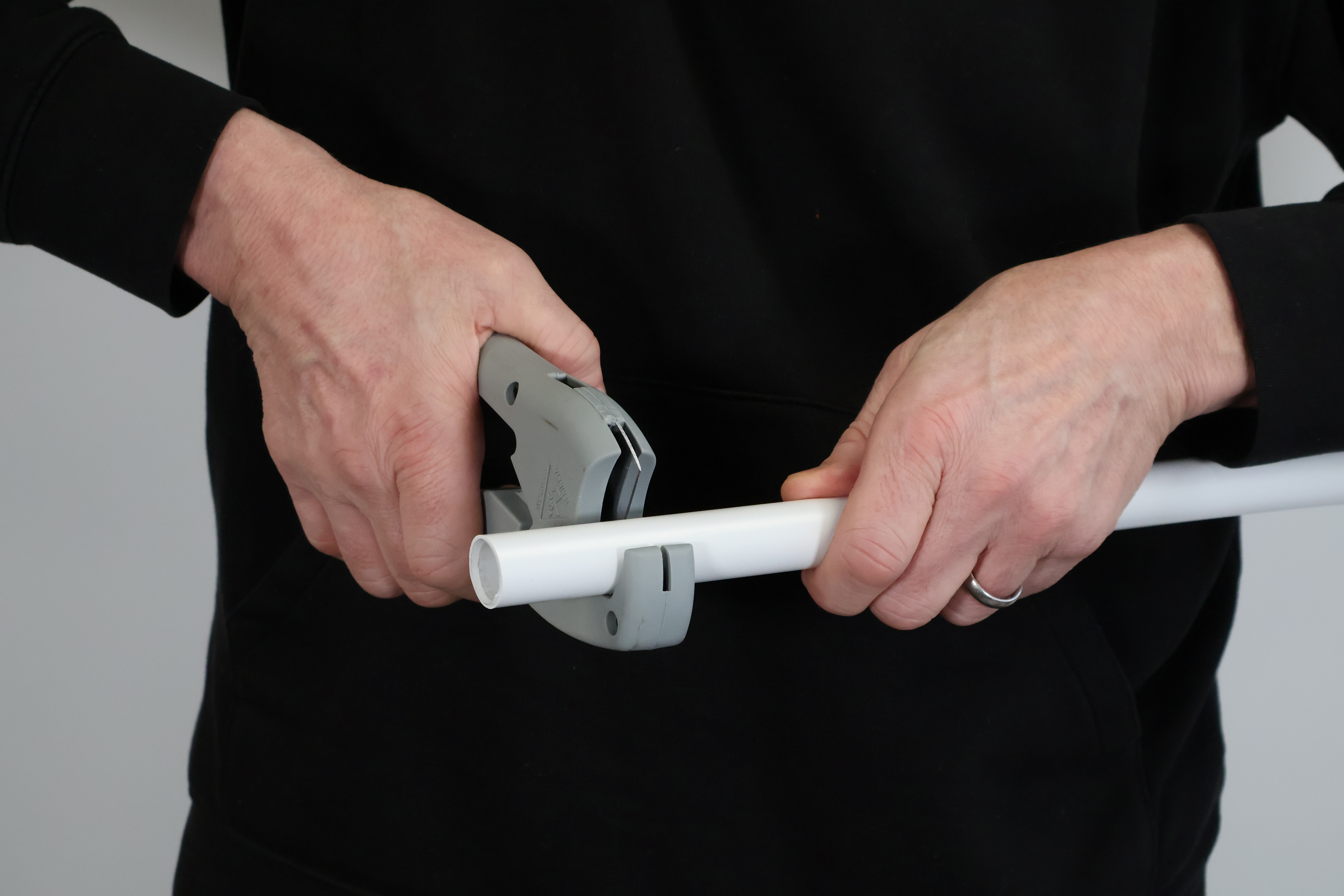 Close-up of plastic pipe shears cutting through 15mm polybutylene barrier pipe. Using a sharp blade ensures a square cut free from burrs, which is critical for protecting the O-ring seal in PolyPlumb and PolyMax fittings.